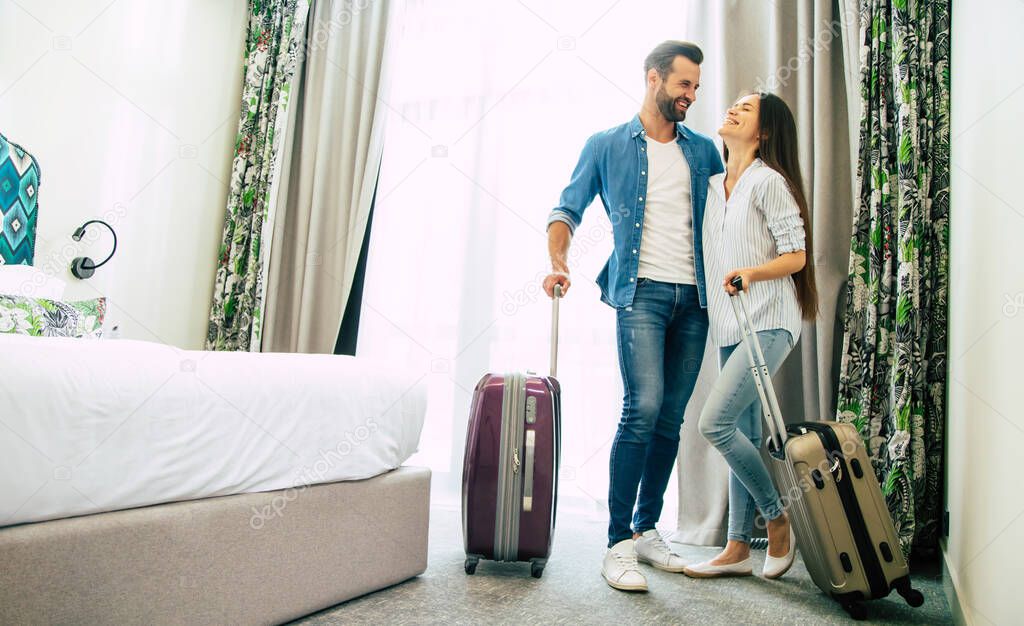 Young beautiful happy excited couple in love with suitcases in a modern hotel during vacation