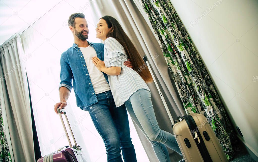Young beautiful happy excited couple in love with suitcases in a modern hotel during vacation
