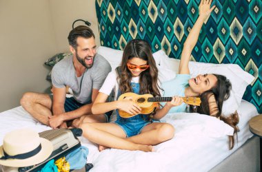 Güzel, genç, mutlu ve heyecanlı bir aile lüks bir otel odasında eşyaları ve kıyafetleri yerleştirip birlikte eğlenirken. Tatil ya da yaz tatili