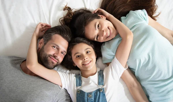 美しい幸せな家族の写真がベッドの上に横たわっていて カメラを見ながら楽しい時間を過ごす — ストック写真