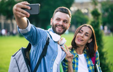 Sırt çantalı güzel mutlu çift akıllı telefondan selfie çekiyorlar.