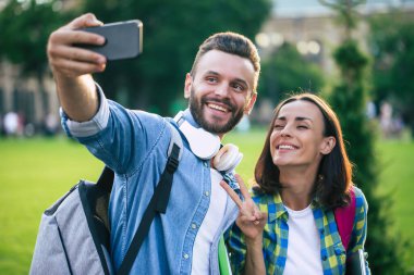 Sırt çantalı güzel mutlu çift akıllı telefondan selfie çekiyorlar.