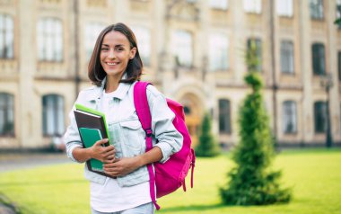 Sırt çantalı güzel, genç ve modern kız dışarıda kameraya bakıyor.