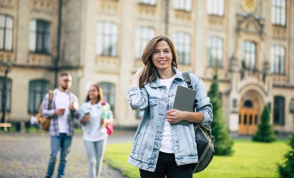 在大学里 一个年轻美丽的女学生背着背包 背着书本 目不转睛地看着自己的朋友们 — 图库照片