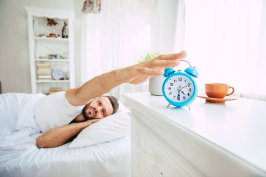 Yakışıklı genç sakallı adamın yakın plan fotoğrafı. Yatakta uzanıyor ve sabah dinleniyor.