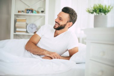 Yakışıklı genç sakallı adamın yakın plan fotoğrafı. Yatakta uzanıyor ve sabah dinleniyor.