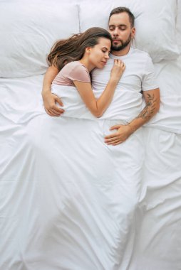 Yatma vakti. Bütün aile uyuyor. Birbirine aşık güzel genç bir çift büyük beyaz yatakta uzanıyor ve dinleniyorlar. Karı koca yatakta birlikteler. Üst görüntü fotoğrafı