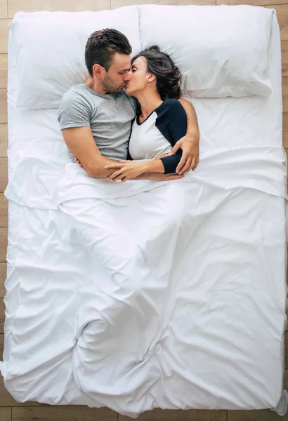 Bedtime. The family are sleeping. Beautiful young couple in love are lying on the big white bed and resting. Husband and wife together in bed. Top view photo