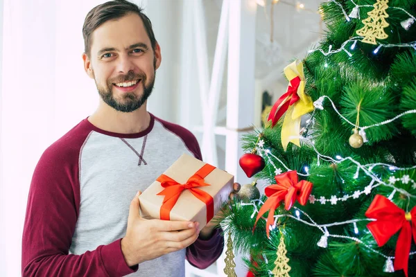 幸せなハンサムな若いですBeaded若いです男でカジュアル服あります上のカメラ上にクリスマスツリーの背景にホームパーティー — ストック写真