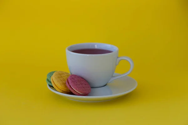 Sarı zemin üzerine çay ile renkli macaroons.