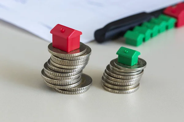 Yığılmış paralar minyatür ev ile.