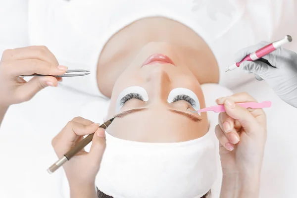 Hands of cosmetologist with different tools around female client laying on pillow, beauty procedures concept.