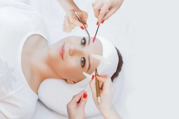 Hands of cosmetologist with different tools around female client laying on pillow, beauty procedures concept.