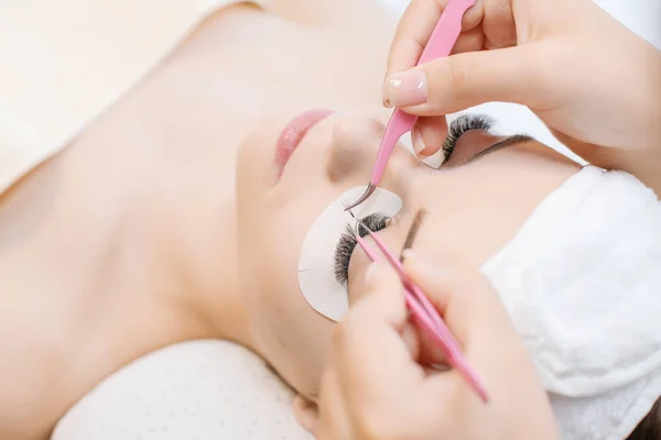 Cosmetologist making eyelash extensions, beauty procedure