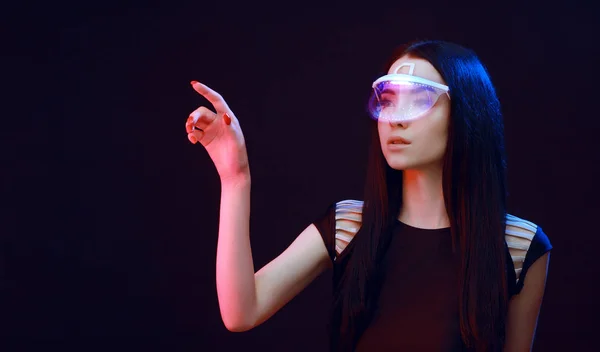 Beautiful woman in futuristic 3d glasses with virtual projection over dark background. Girl in glasses of virtual reality. Augmented reality, science, future technology, robots and people concept. VR.