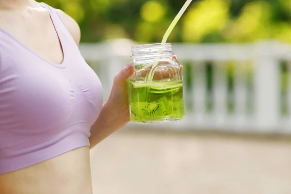 Sports woman drinking detox water or lemonade outdoor.