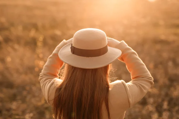 rear view of woman wearing hat in sunset light