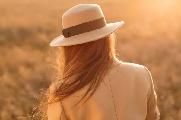 rear view of woman wearing hat in sunset light