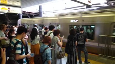 Tokyo, Japonya - Ağustos 2018: commuters sırada beklerken bir metro istasyonu platformu gelen tren