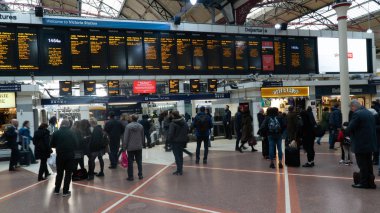 Victoria istasyonunda elektronik kart üzerinde zaman çizelgesine bakan yolcular, Londra, İngiltere