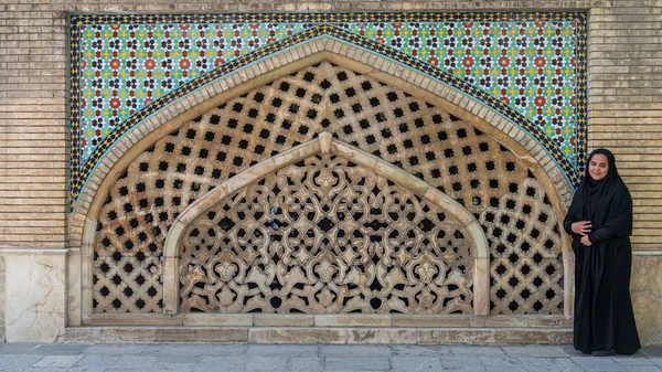 En iransk kvinde, der stod op ad en flisebelagt mur i gården på Golestan-paladset, Teheran, Iran - Stock-foto