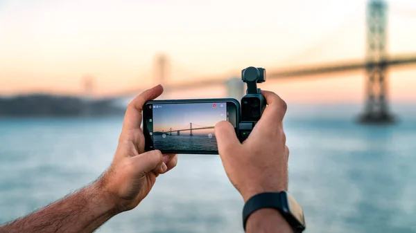 Bir fotoğrafçı Dji Osmo Pocket 'i San Francisco, Usa' daki Bay Bridge 'in görüntülerini çekmek için kullanıyor.