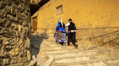 Unidentified iranian couple in traditional persian clothes climbing stairs, Masuleh, Gilan province, Iran clipart