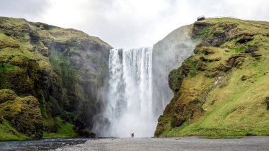 İzlanda 'nın güneyinde Skogar' da fotoğraf çeken bir çiftle birlikte Skogafoss 'un büyük şelalesi.