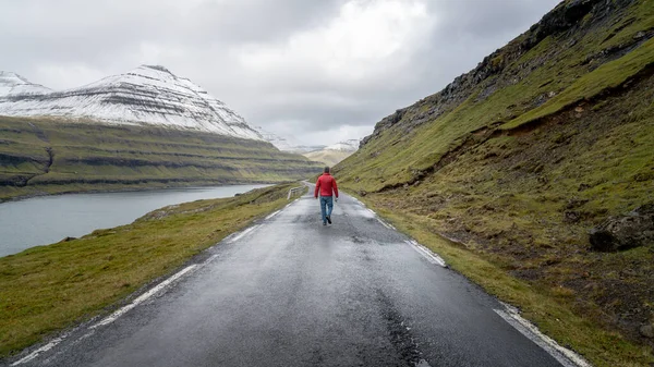 Hombre no identificado caminando en el paisaje dramático de la carretera, Islas Feroe — Foto de Stock