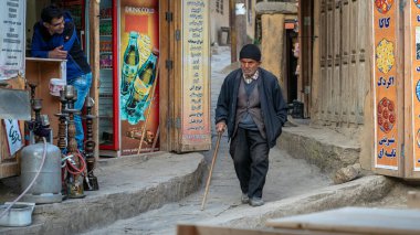Iranian old man walking in the narrow road of Masuleh village, Gilan, Iran clipart