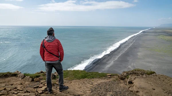 Невідомий чоловік, що дивиться на вулканічний чорний піщаний пляж, розташований у Вік - Ісландія. — стокове фото