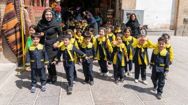 Bir grup öğrenci ve öğretmenleri İran, İsfahan 'da bir sokakta yürüyorlar.