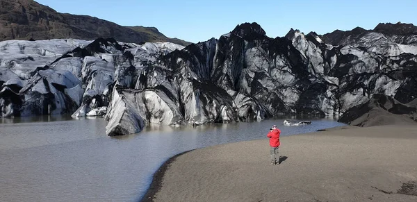 Ongeïdentificeerde man die een foto neemt van de Solheimajokull uitlaatgletsjer en de gletsjerlagune, IJsland — Stockfoto