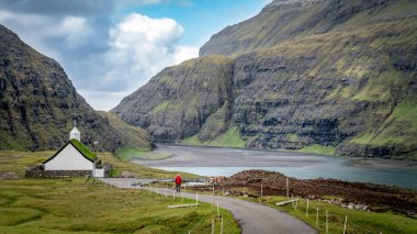 Danimarka 'nın Faroe Adaları, Saksun köyünden kiliseye doğru yürüyen kimliği belirsiz bir adam var.