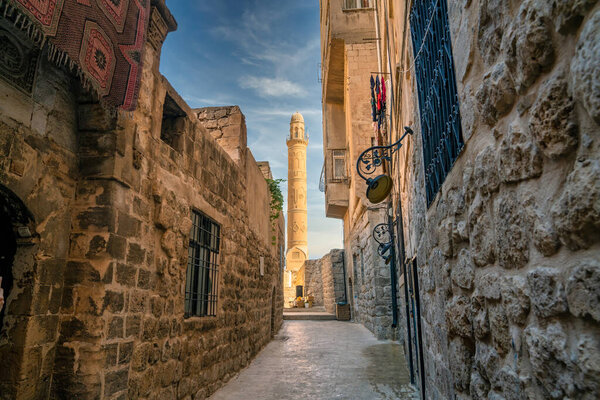 Mardin, Turkey - January 2020: Minaret of Ulu Cami, also known as Great mosque of Mardin as seen from a narrow Mardin street
