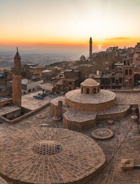 Mardin, Turkey - January 2020: Old city of Mardin cityscape with roof of a Turkish hammam and minarets during sunset