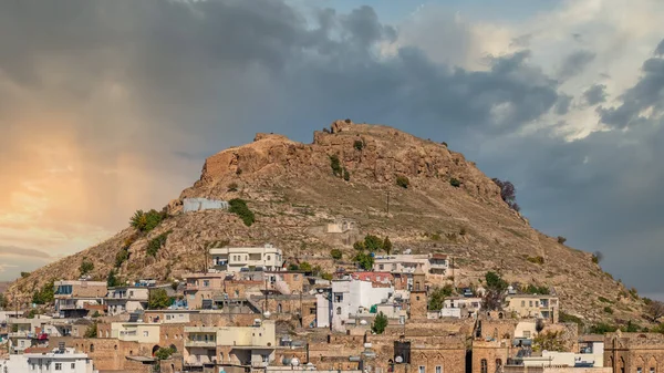 Savur, Mardin, Türkiye - Ocak 2020: Gökyüzü dramatik bir tepenin üzerinde eski taş evleri olan Savur Kasabası