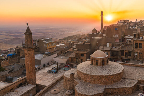 Mardin, Turkey - January 2020: Old city of Mardin cityscape with roof of a Turkish hammam and minarets during sunset