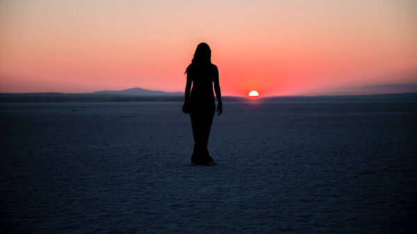 Ankara, Turkey - August 2013: Silhouette of an unidentified woman watching the sunset at Salt Lake Tuz Golu in Ankara, Turkey