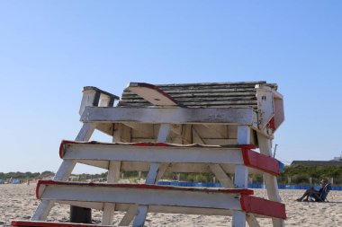 Kumsalda kumsalda oturan yıpranmış cankurtaran sandalyesi.