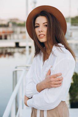 Şık bir kadın, sıcak bir yaz gününde gün batımında sahilde yürüyor.