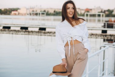 Mutlu, şık bir kadın, sıcak bir yaz gününde gün batımında sahilde yürüyor.