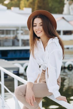 Mutlu, şık bir kadın, sıcak bir yaz gününde gün batımında sahilde yürüyor.