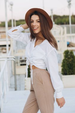 Mutlu, şık bir kadın, sıcak bir yaz gününde gün batımında sahilde yürüyor.