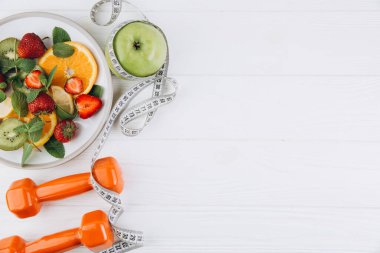 Diyet planı, menü veya program, mezura, su, dambıl ve beyaz arka planda taze meyve diyeti, kilo kaybı ve detoks konsepti, üst görünüm