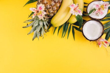 Yaz meyveleri. Sarı arka planda tropik palmiye yaprakları, ananas, hindistan cevizi ve muz. Düz konum, üst görünüm, kopyalama alanı