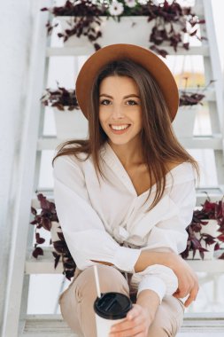 Havalı bir kadın plajda bir kulüpte dinleniyor ve ılık bir yaz gününde kahve içiyor.