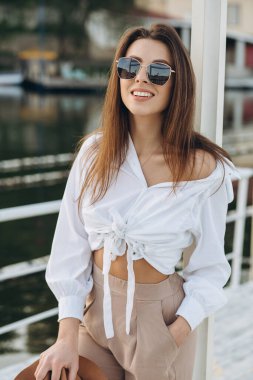 Mutlu, şık bir kadın, sıcak bir yaz gününde gün batımında sahilde yürüyor.