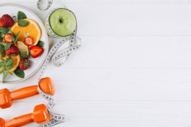 Diyet planı, menü veya program, mezura, su, dambıl ve beyaz arka planda taze meyve diyeti, kilo kaybı ve detoks konsepti, üst görünüm