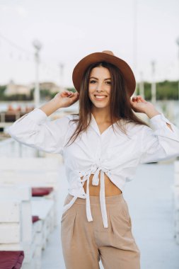 Şık bir kadın, sıcak bir yaz gününde gün batımında sahilde yürüyor.